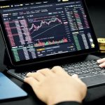 An image showing a man using a tablet to trade bitcoins in the cryptocurrency market.